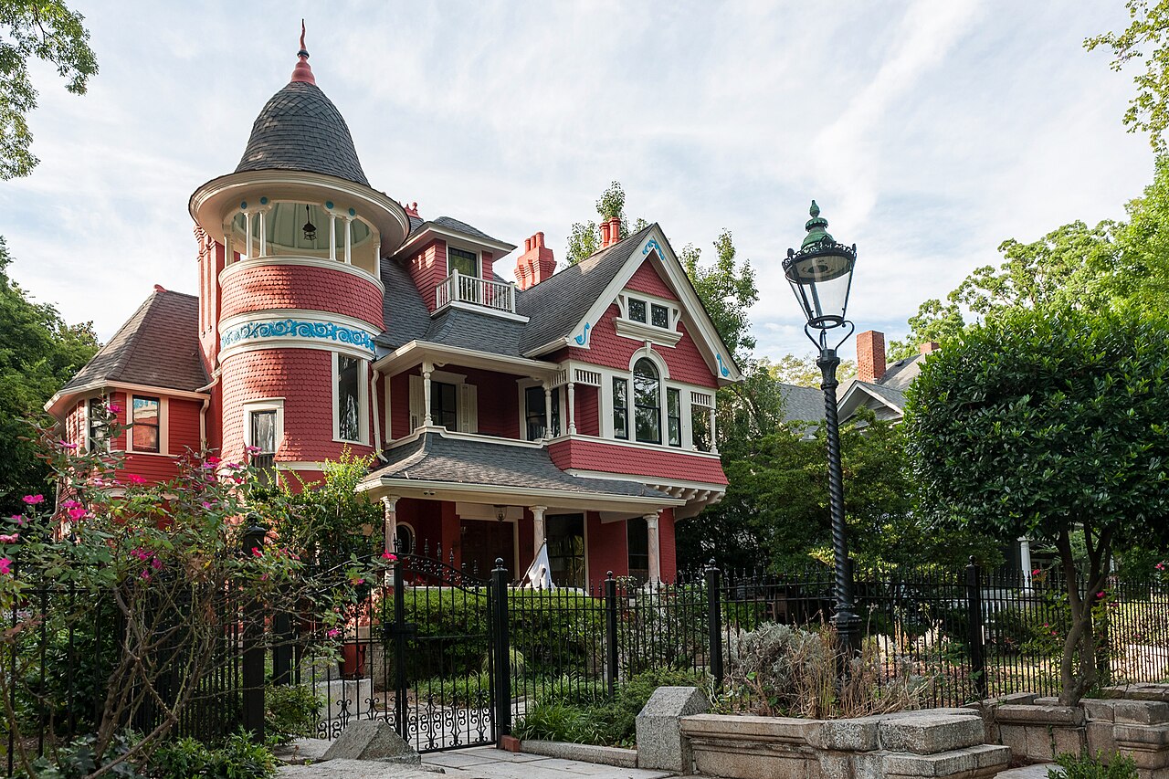 A Victorian house with a turret, iron railings and an overgrown front garden